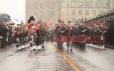 2012 Memorial Service - Officers with bagpipes marching in front of onlookers on wet street